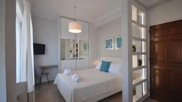 Ein Schlafzimmer mit Bett, Schreibtisch, Stuhl, Fernseher und einer Tür mit Holzverkleidung.