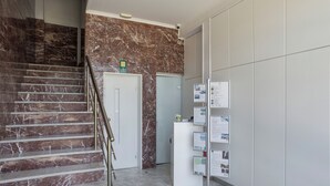 Eine Marmortreppe, ein Empfangstresen mit Informationsschildern und eine Tür.