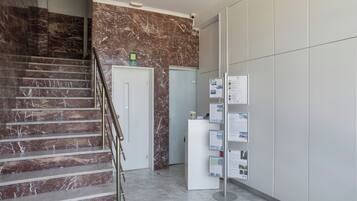 Eine Marmortreppe, ein Empfangstresen mit Informationsschildern und eine Tür.
