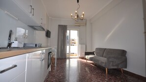 Eine moderne Küche mit Essbereich, einem grauen Sofa und einem großen Fenster mit Vorhängen.