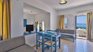 Una sala de estar moderna con comedor, un sofá, un televisor y vista al mar.