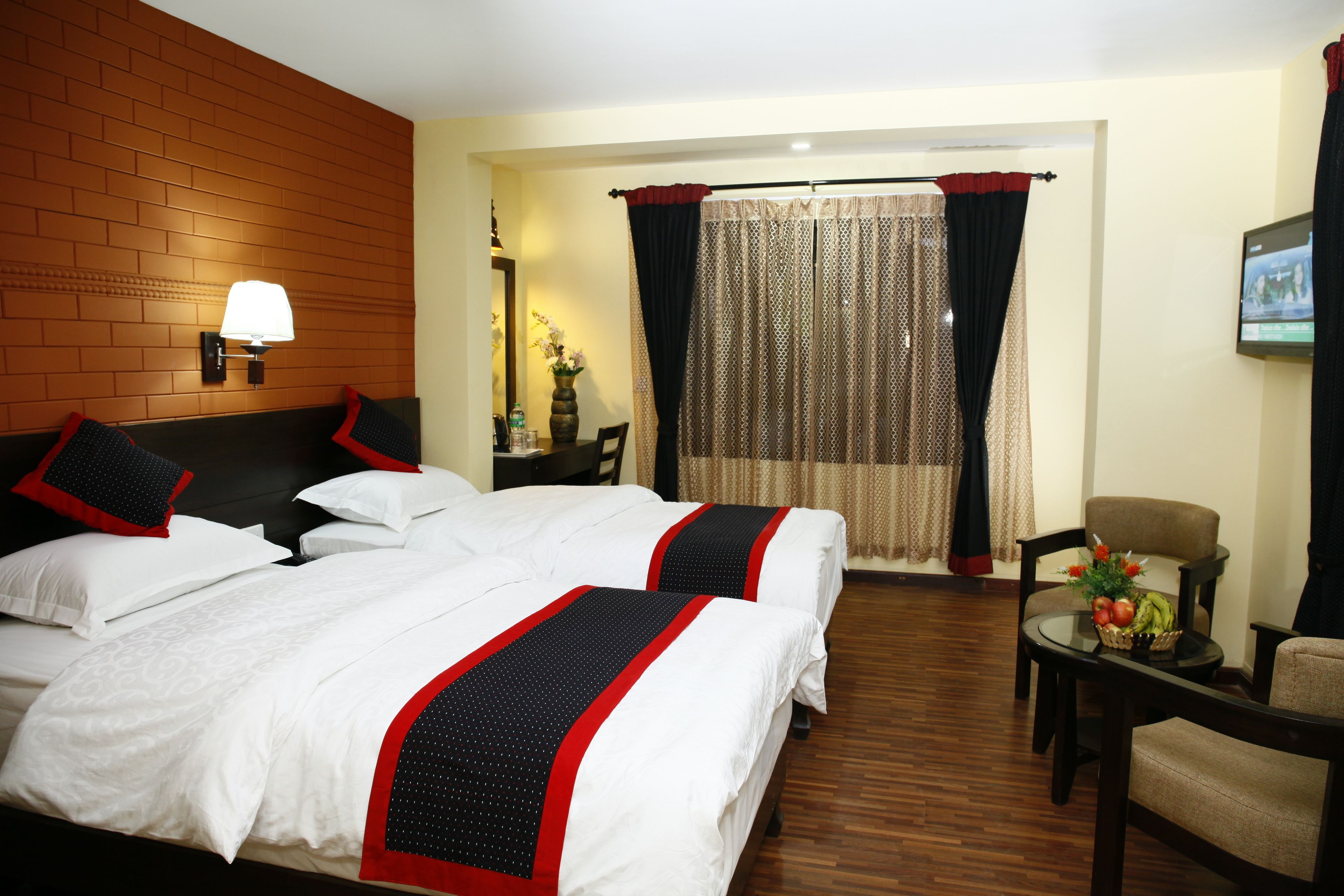 Une chambre d’hôtel avec deux lits, un coin salon avec une table et des chaises, et un téléviseur fixé au mur.