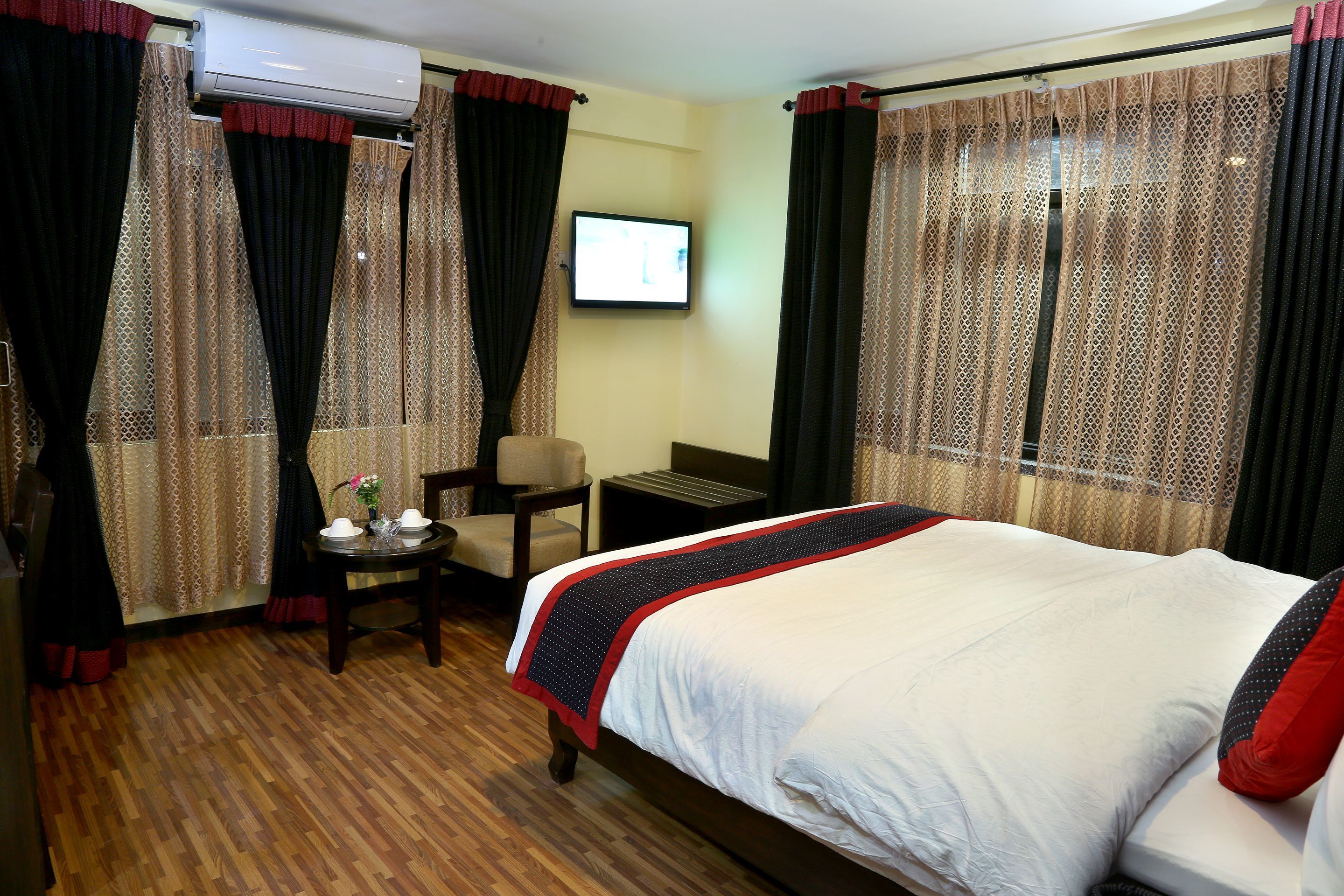 Una habitación de hotel con una cama grande, un escritorio con una silla, un televisor y cortinas.