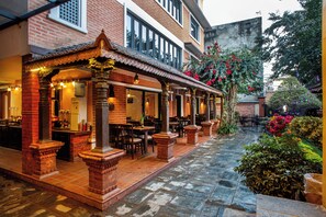 A restaurant with outdoor seating, brick columns, and a tiled patio. - Taleju Boutique Hotel (Kathmandu)