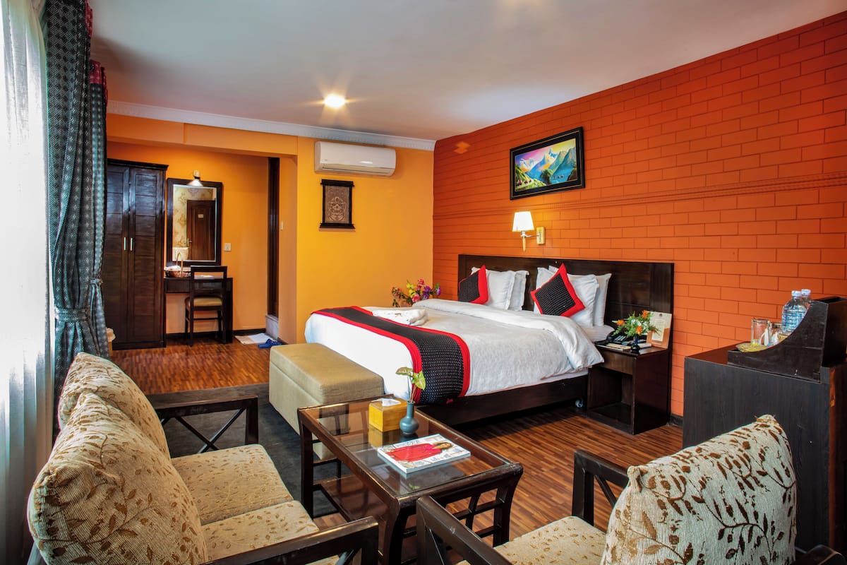 A hotel room with a bed, a desk, a chair, and a sofa.