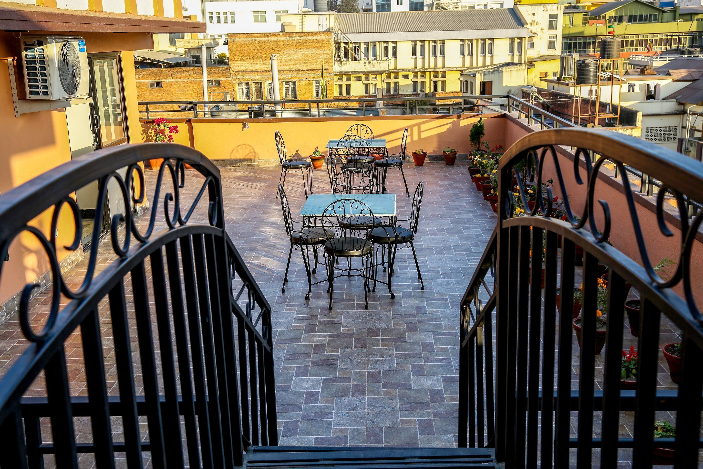 Une terrasse sur le toit, avec une table et des chaises, des plantes en pot et une vue sur le paysage urbain.