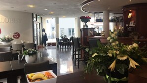 Een hal met een receptiebalie, een zithoek en een bar.