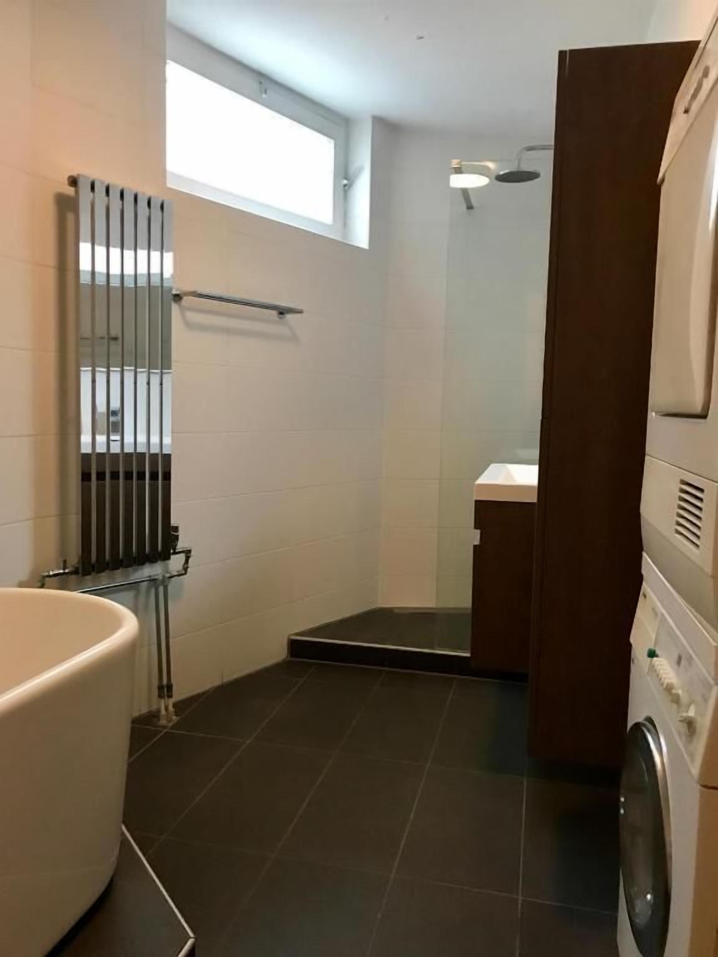A bathroom with a bathtub, a shower, and a washing machine.