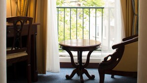 Een kamer met een ronde tafel, twee stoelen, een lamp en een raam met gordijnen.