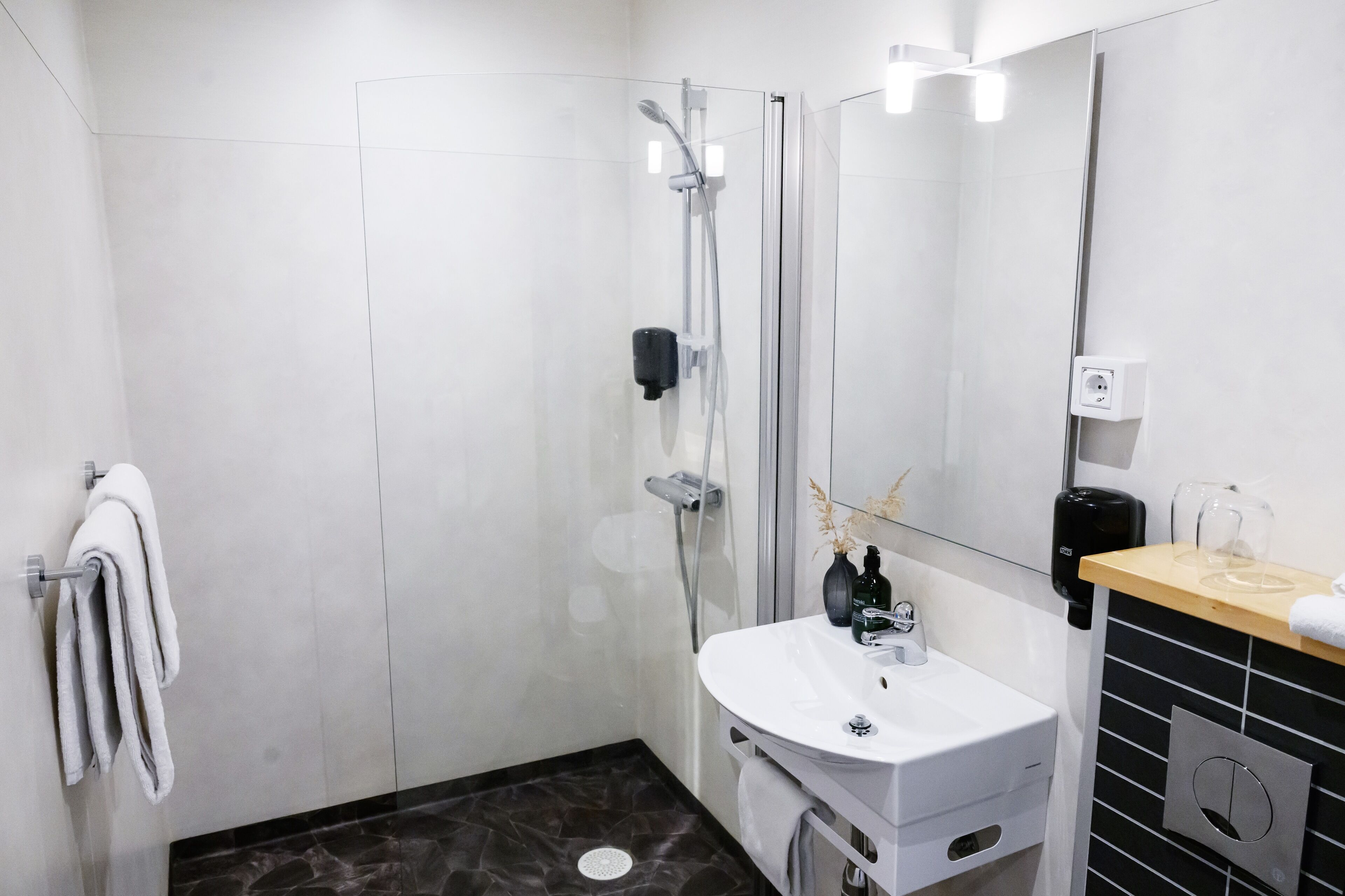 A modern bathroom with a glass-enclosed shower, a white sink, and a mirror.
