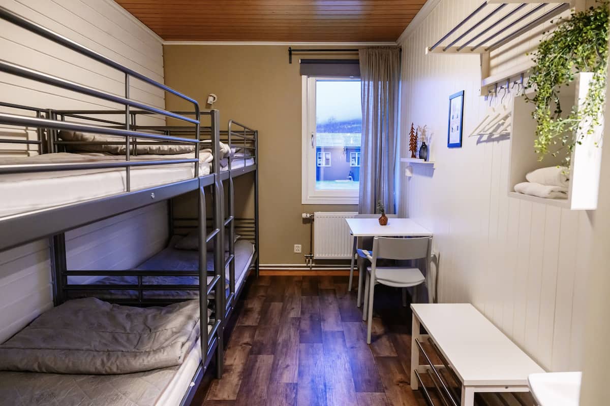Un dormitorio con literas, un escritorio pequeño y una ventana con vista a un edificio.