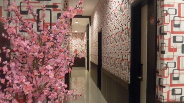 A corridor with patterned wallpaper and a cherry blossom tree. - Harmoni Inn Pelabuhan Makassar (Makassar)