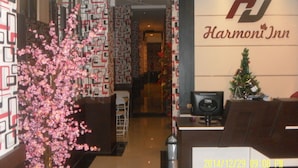 A hotel reception area with a decorative cherry blossom tree, a Christmas tree, and a sign for 'Harmoni Inn'. - Harmoni Inn Pelabuhan Makassar (Makassar)