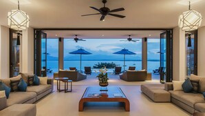 Un vaste espace de vie avec vue sur la mer, aménagé avec des canapés et une table basse.
