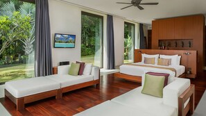 Una habitación de hotel moderna con una cama grande, dos sofás blancos, un cabecero de madera y vistas al exterior.
