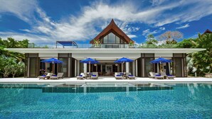 Un complexe hôtelier moderne doté d’une piscine, de chaises longues et de parasols bleus.