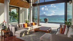 Un salon moderne avec un ensemble de canapés, une table basse et une vue sur la mer grâce à de grandes fenêtres.