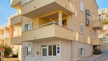 Un edificio residencial de varios pisos con balcones, unidades de aire acondicionado y una antena parabólica.