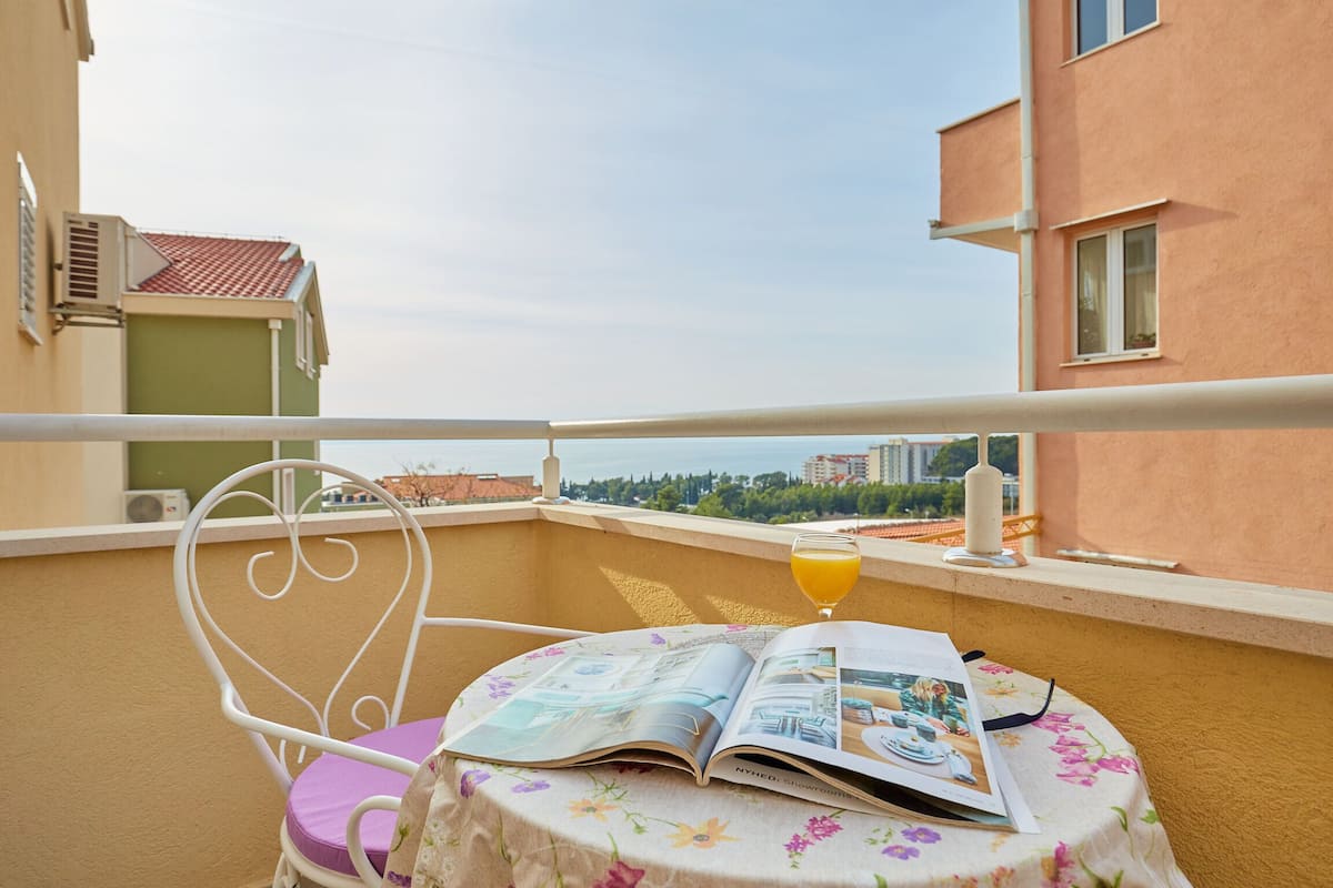 A balcony with a table, a chair, and a glass of orange juice.