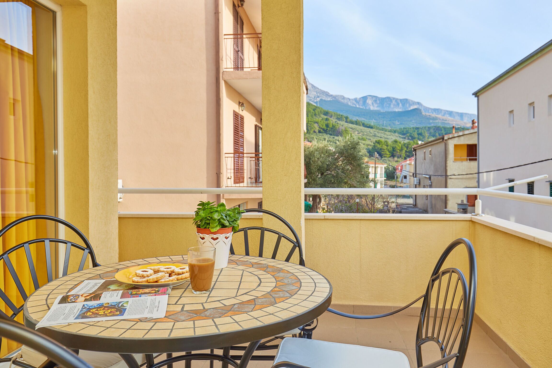 A round table with chairs on a balcony, a potted plant, and a menu.