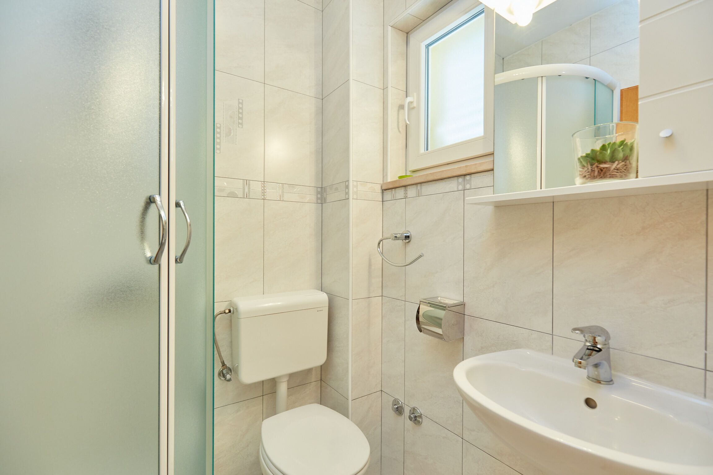 Ein Badezimmer mit Toilette, Waschbecken und einer Duschkabine aus Glas.