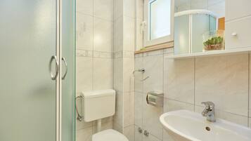 Ein Badezimmer mit Toilette, Waschbecken und einer Duschkabine aus Glas.