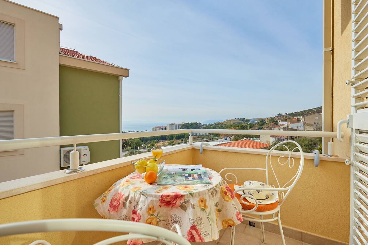 A balcony with a table, chair, and a bowl of fruit.
