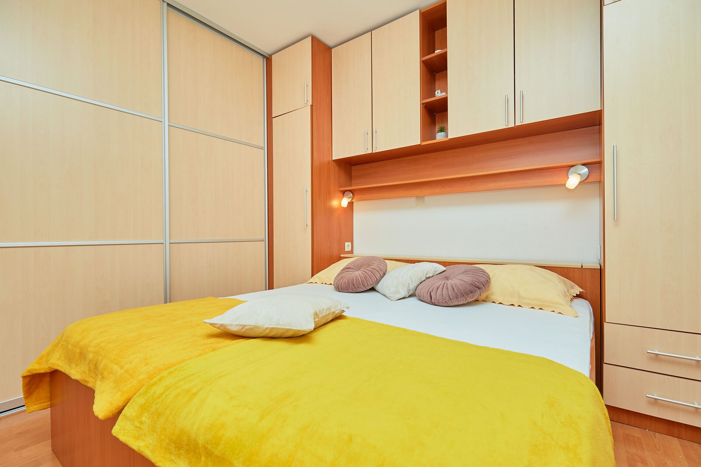 A bedroom with a bed, wooden wardrobe, and built-in shelves.