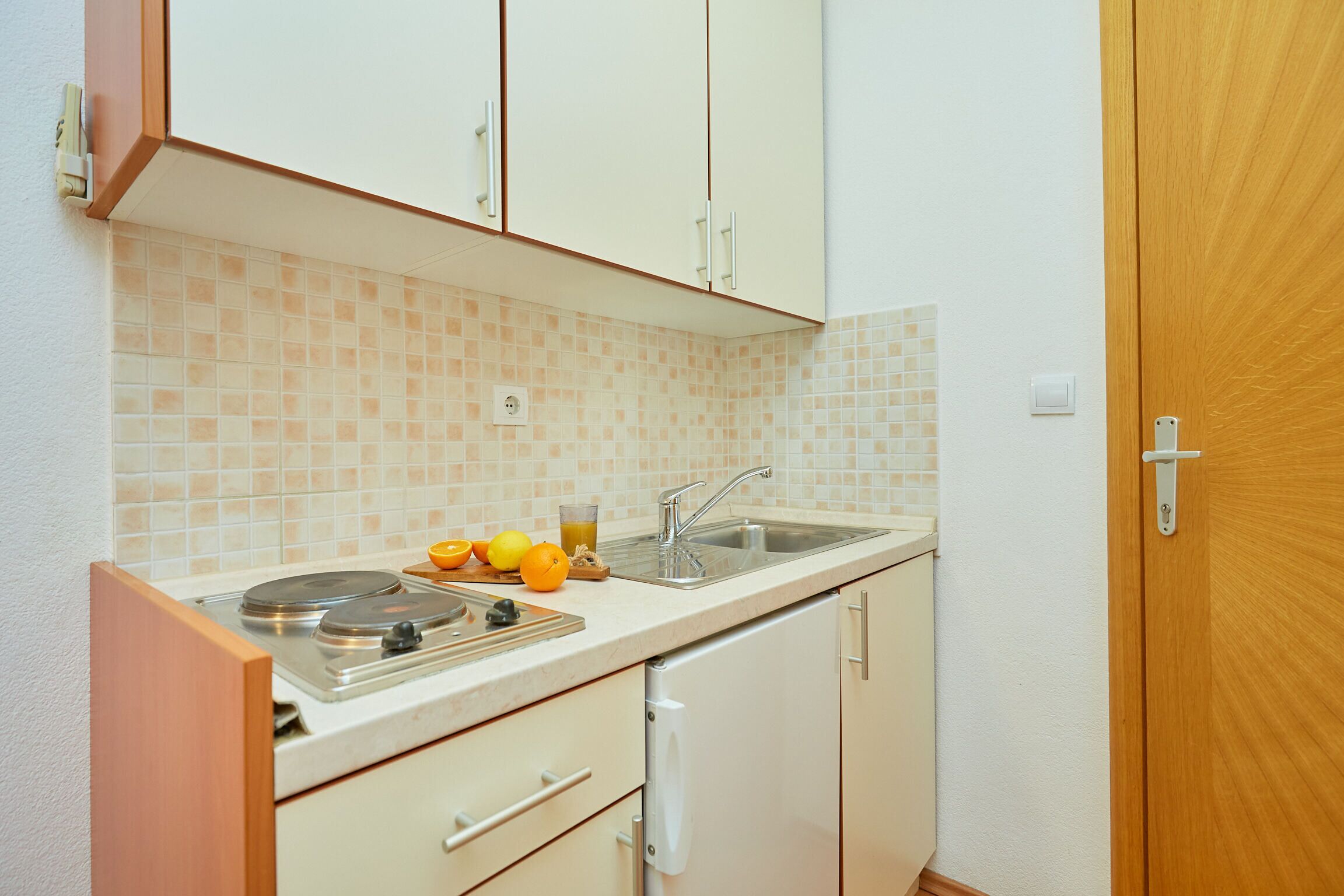 Una cocina compacta con lavamanos, encimera y armarios.