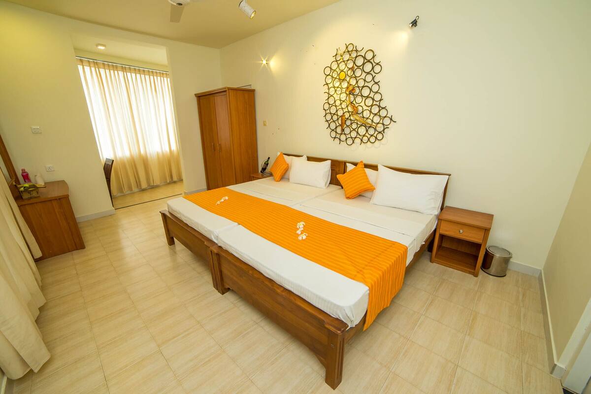 A bedroom with a large bed, wooden headboard, and an orange bedspread. There is a wooden nightstand and a wardrobe.