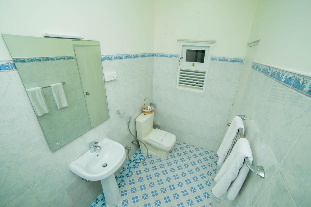 Casa de banho com lavatório, sanita e pequena janela com ventilação.