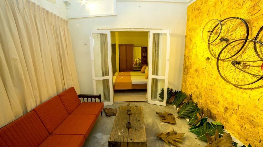 Una habitación con un sofá rojo, una mesa de madera y una pared amarilla decorada con ruedas de bicicleta.