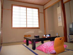 Una habitación tradicional japonesa con suelo de tatami, una mesa baja y un televisor.