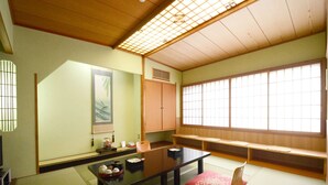 A traditional Japanese room with tatami flooring, a low table, a cushioned bench, and sliding doors. - Hanagoyomi (Nanao)