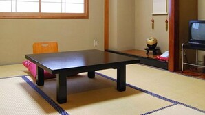 A tatami mat room with a low table, a chair, a television, and a cabinet. - Hanagoyomi (Nanao)