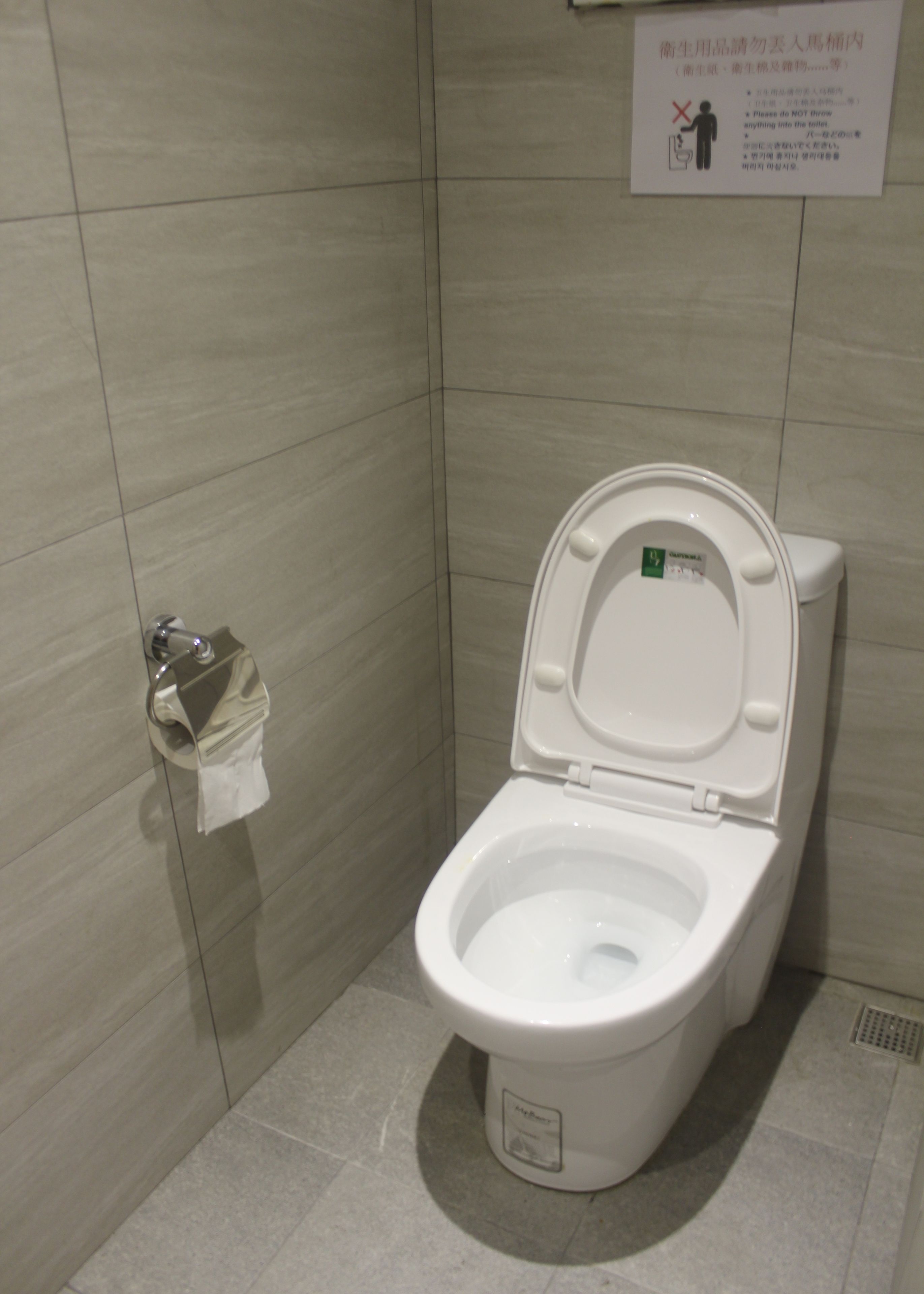 A white toilet with a closed lid in a bathroom with tiled walls and floor.