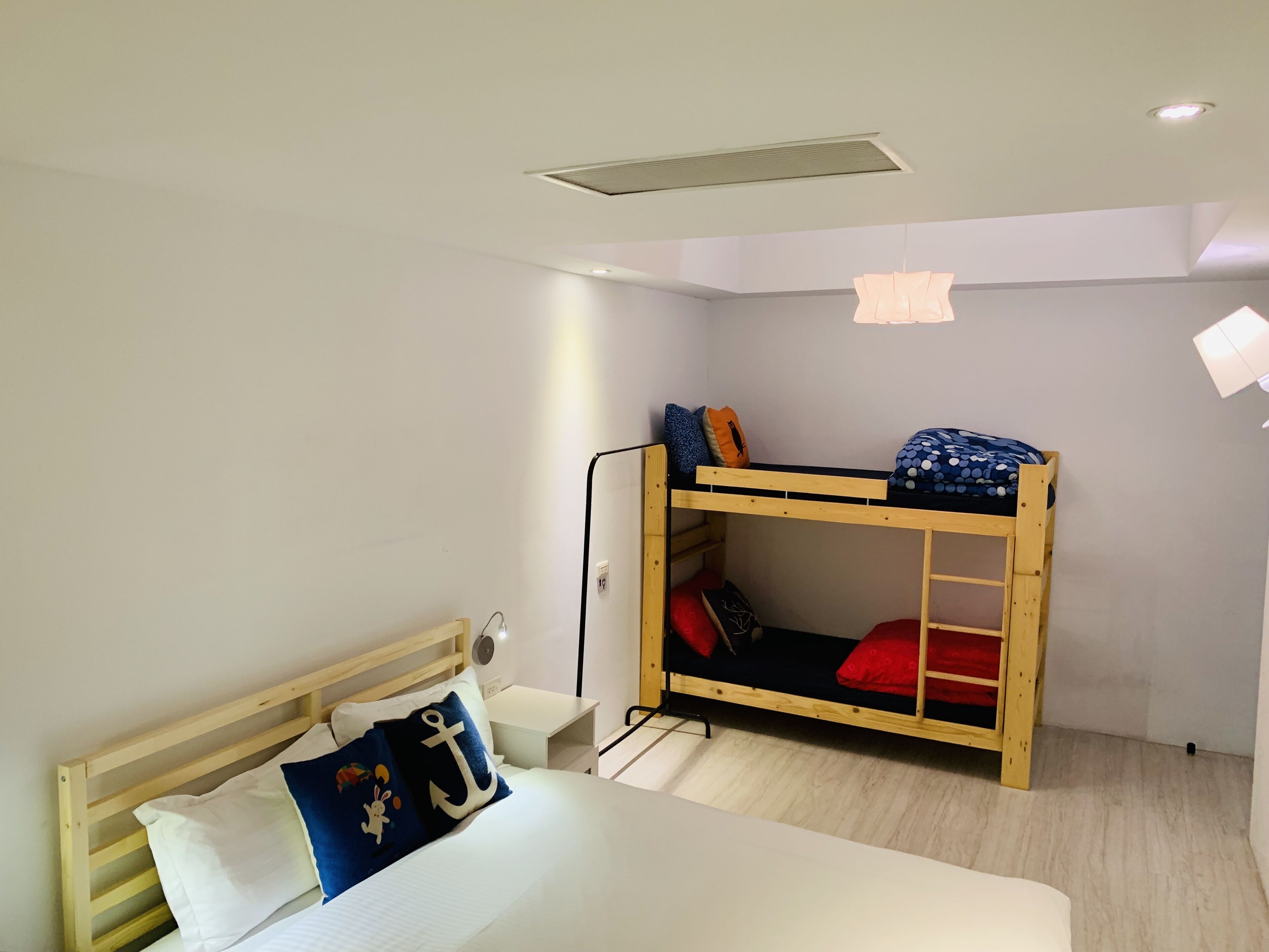 A room with a bunk bed, a single bed, a desk, and a chair.