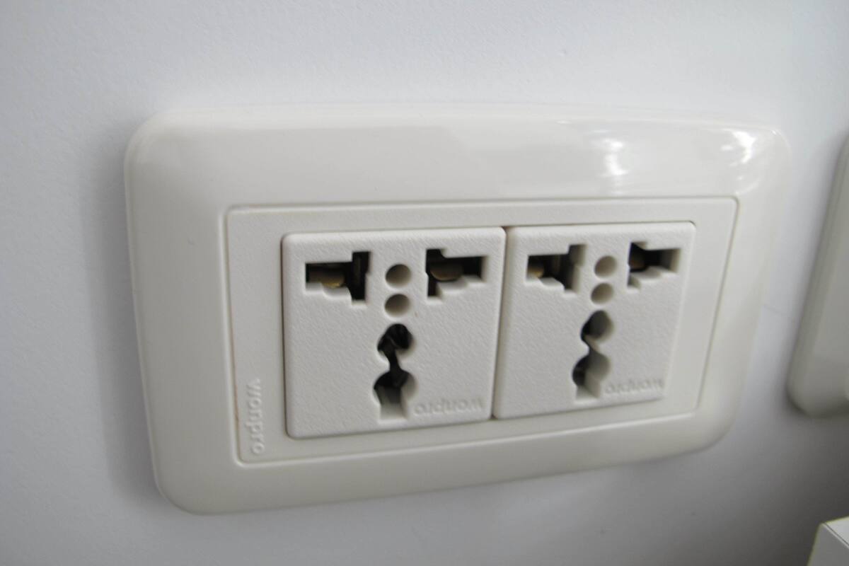 A white electrical outlet with two sockets, a switch, and a grounding hole.