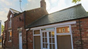 Un bâtiment en briques de deux étages, doté d’une grande fenêtre et d’une porte blanche.