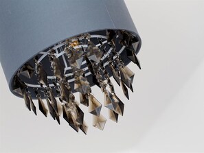 A chandelier with multiple crystal-like elements hanging from a grey, cylindrical structure. - Luxurious Serviced Apartments (Leeds)