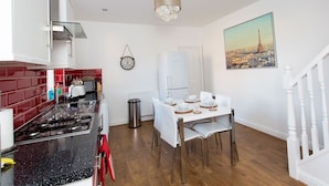 Une cuisine moderne avec un coin repas, comprenant une cuisinière, un évier et des meubles de rangement blancs.