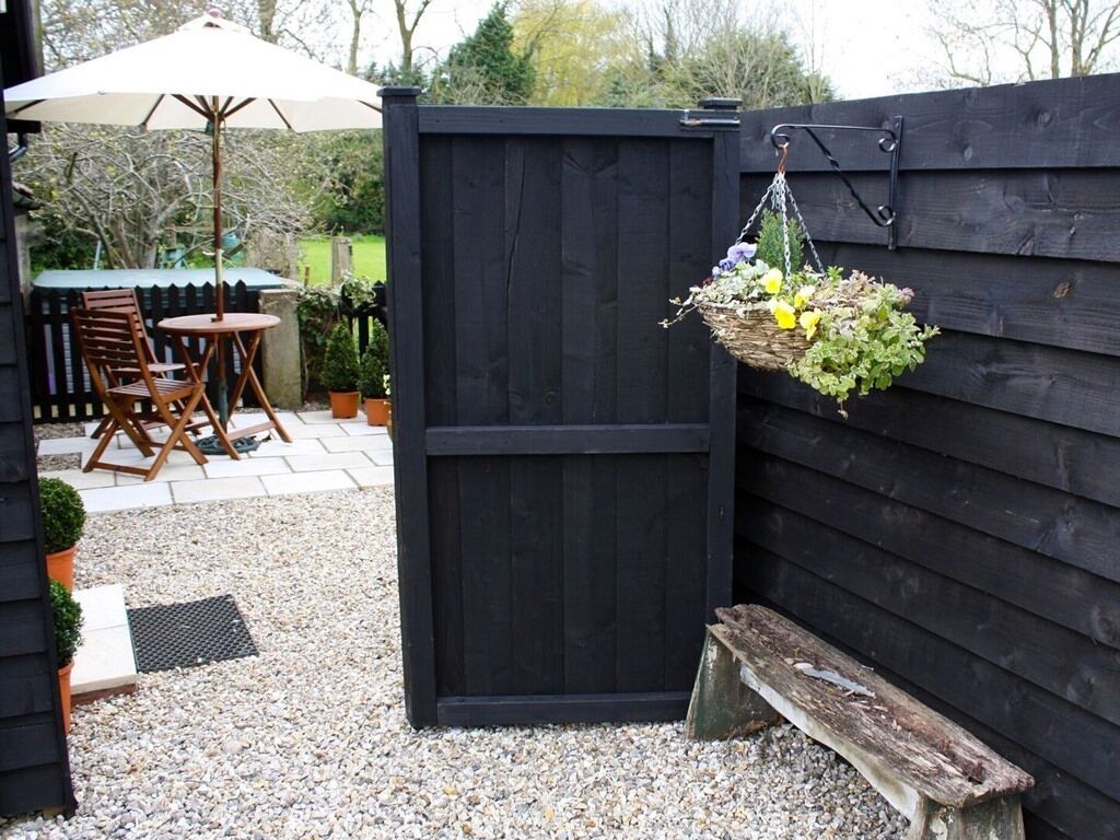 A wooden gate, a bench, and a hanging basket with flowers.