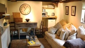 A cozy living room with a sofa, a wooden coffee table, a dining table, and a kitchen area in the background. - Riverside House (Norwich)