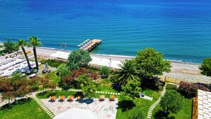 A beachside hotel with outdoor seating, a pool, and a pier extending into the sea. - Rawda Resort Hotel Altinoluk (Edremit)