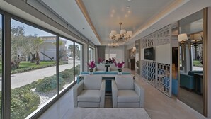 A modern hotel lobby with a reception desk, seating area, and large windows offering a view of the outdoors. - Rawda Resort Hotel Altinoluk (Edremit)