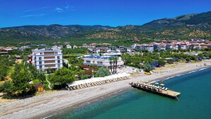 A coastal resort with beachfront villas, a pier, and a backdrop of mountains. - Rawda Resort Hotel Altinoluk (Edremit)