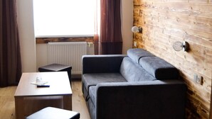Un salón moderno con pared de madera, un sofá gris, una mesita y una ventana con cortinas.