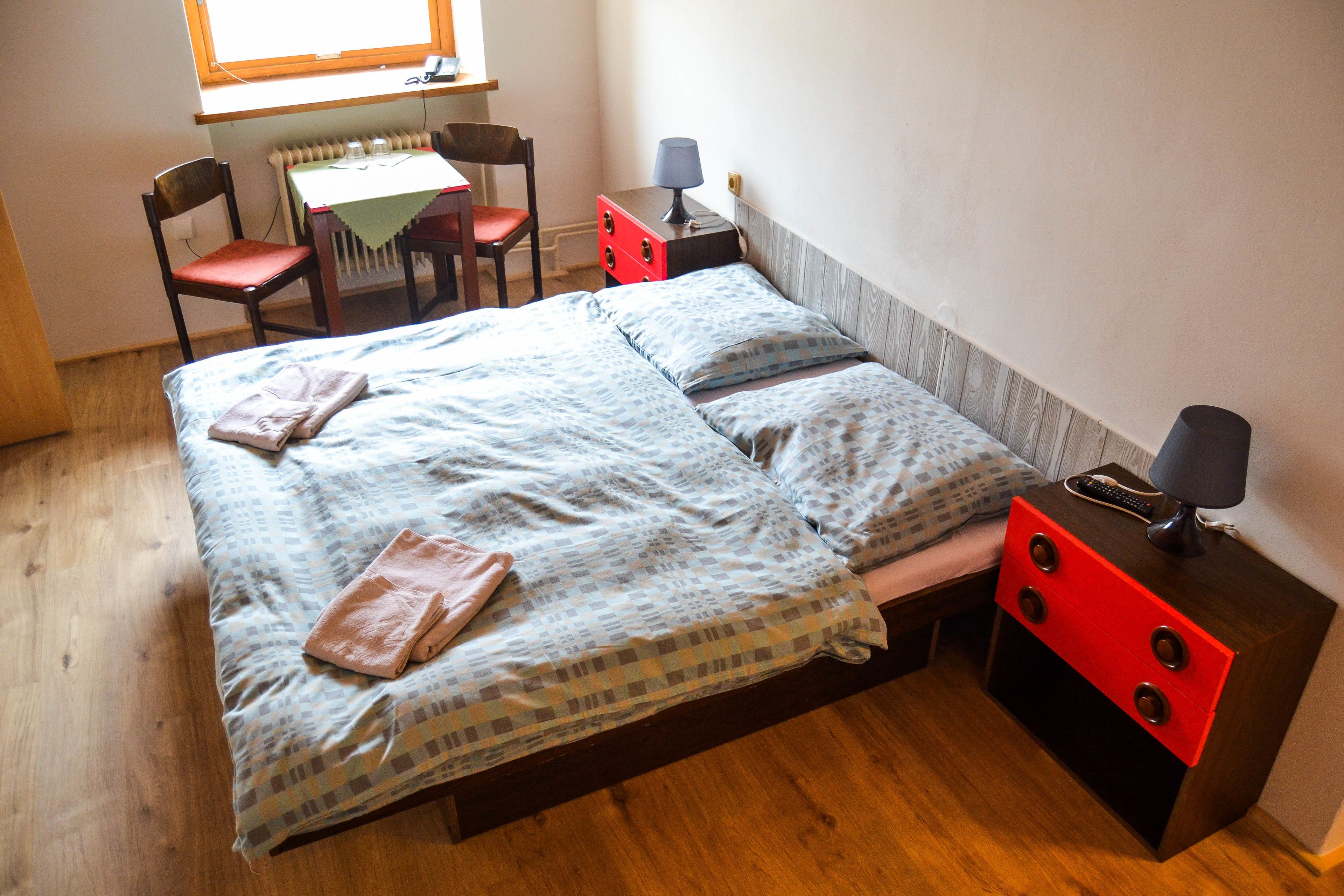 A bedroom with a bed, a desk, a chair, and a nightstand.