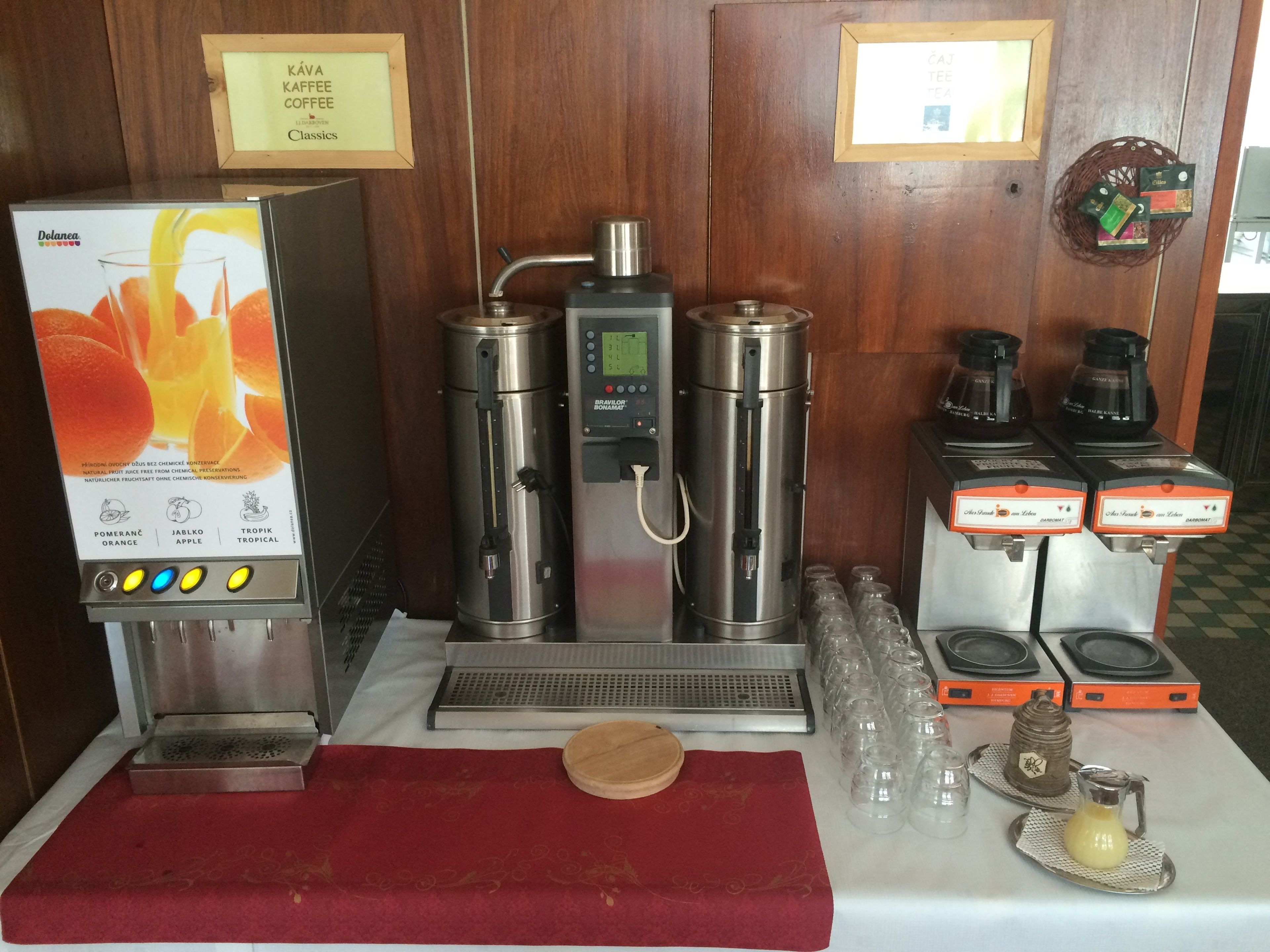 Angolo caffè con macchina da caffè, diversi erogatori e cartello che indica la disponibilità di caffè e tè.