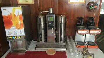 Angolo caffè con macchina da caffè, diversi erogatori e cartello che indica la disponibilità di caffè e tè.